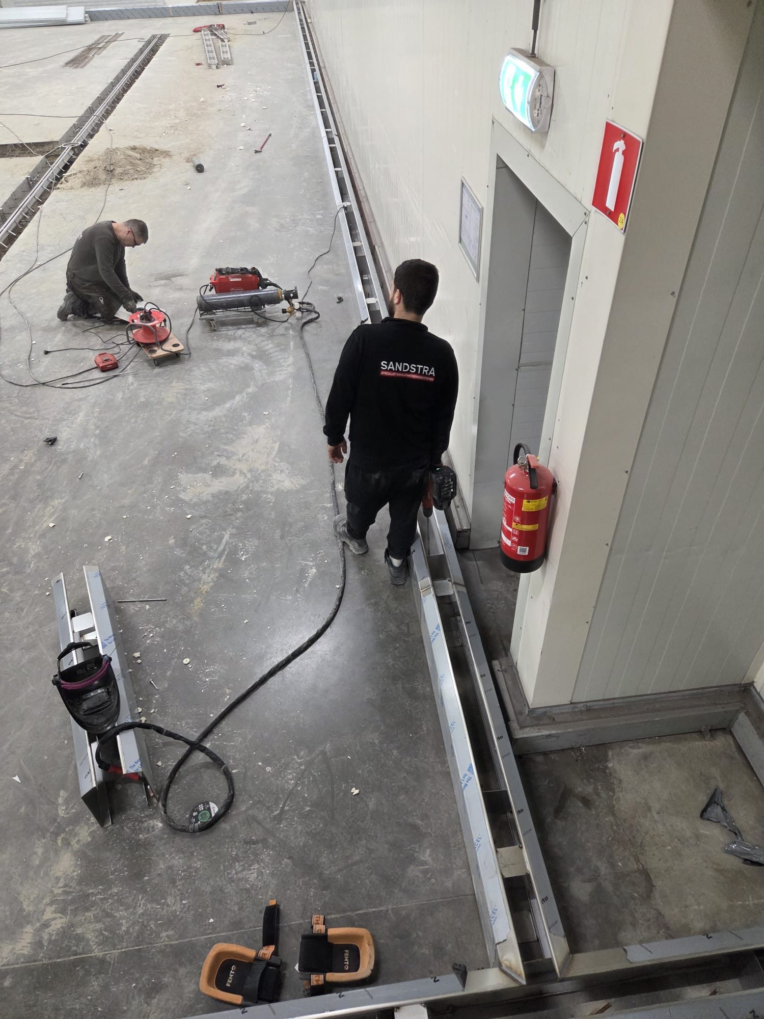 Eigen vakmensen van Sandstra RVS aan het werk met de RVS vloergoten op locatie